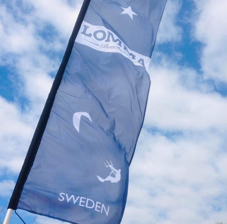 Lomma Beachwear-flagga mot blå himmel
